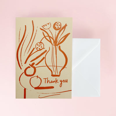 Greeting card with floral design and 'Thank you' text on beige background and a white envelope