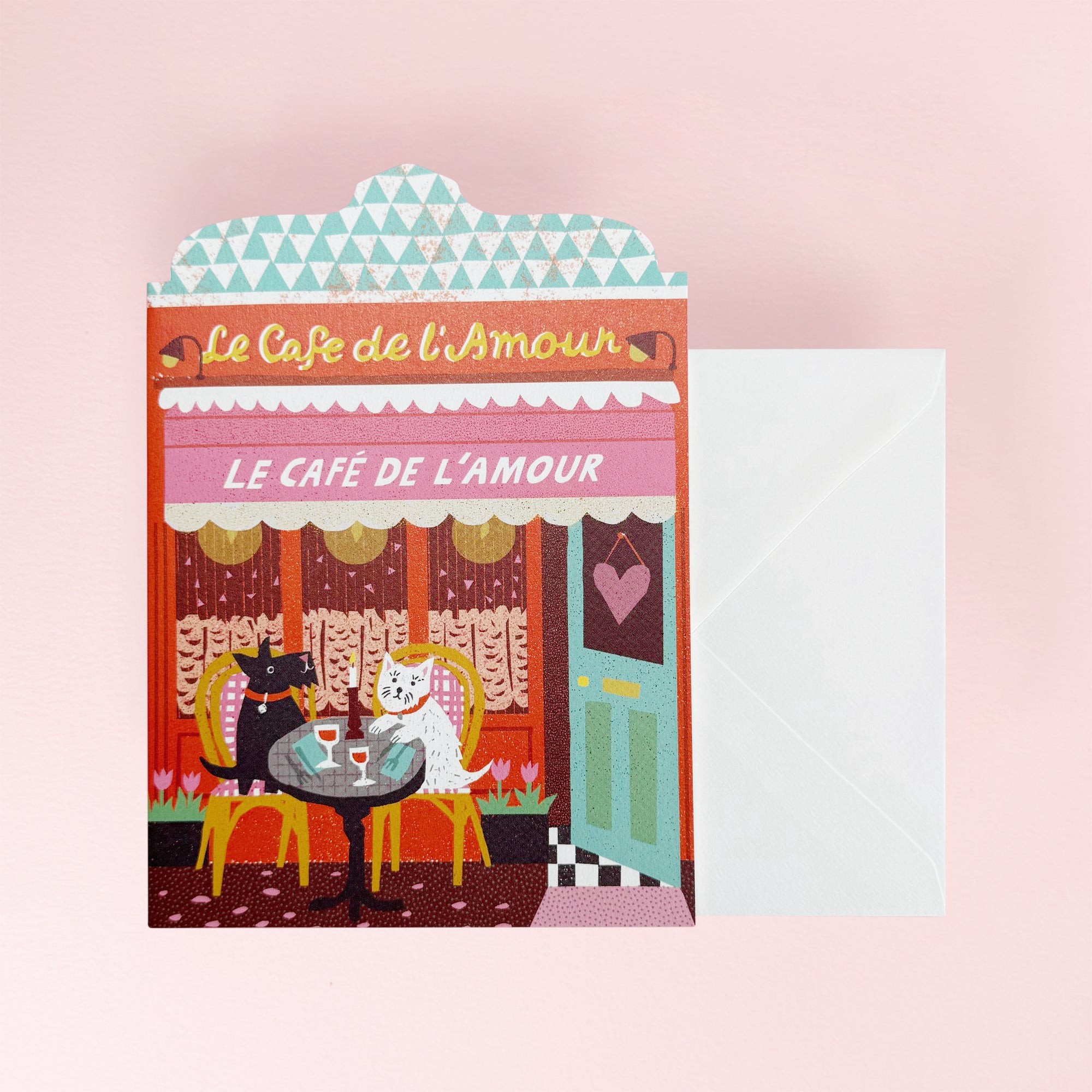 Greeting Card Illustrated card of 'Le Cafe de l'Amour' with a dog couple at a table, on a pink background.