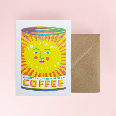 Card with coffee can design and envelope on a pink background